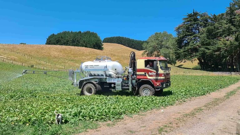 Tow and Fert Multi 4000 sprayer mounted on a truck, applying liquid fertiliser to a green crop field with its spray boom.